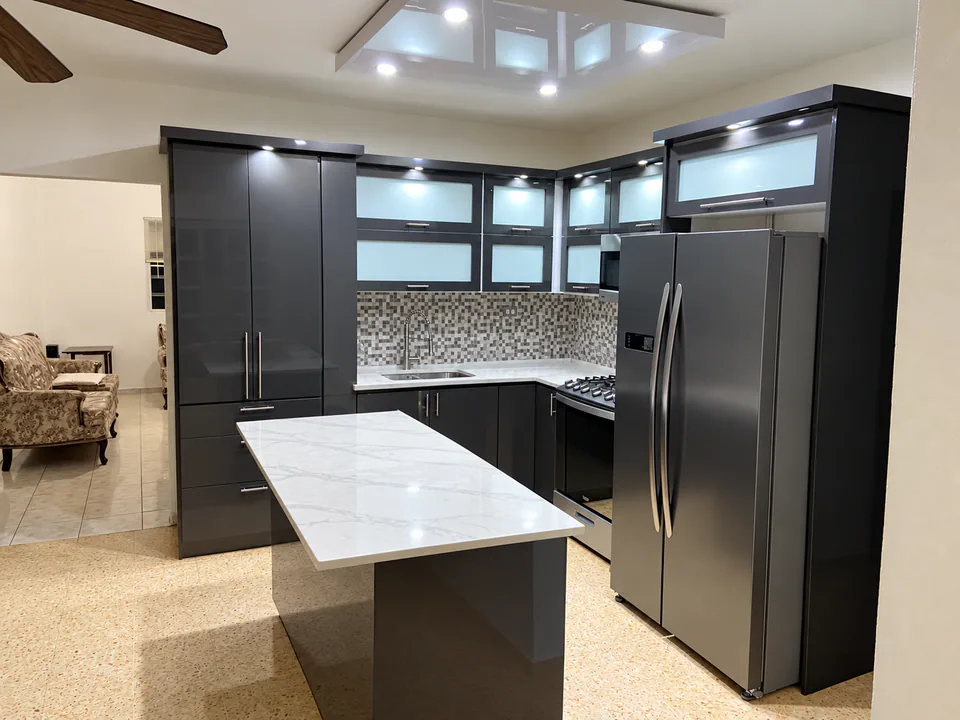 Cocina contemporánea realizada por M5 con gabinetes oscuros, iluminación integrada e isla de superficie clara.